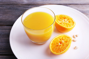 Glass of juice and ripe sweet tangerine on wooden table