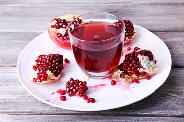 Ripe pomegranate and glass of juice on wooden table