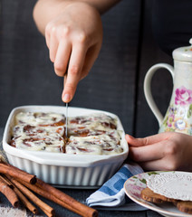 cut buns Cinnabon cinnamon and nuts in baking dish, hands