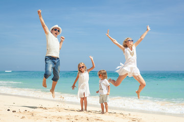 Happy family jumping on the beach on the day time