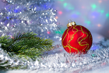Fototapeta na wymiar Red Christmas ball and tree branch on the background lights garl