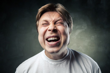 young angry man over dark grey background