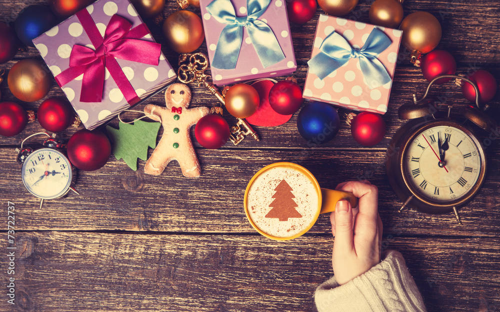 Wall mural female holding cup of coffee with cream christmas tree on a tabl