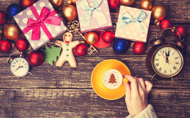 Female holding cup of coffee with cream christmas tree on a tabl