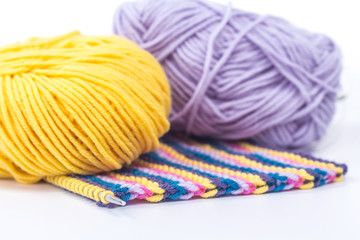 Two ball of wool with a striped piece of knitting