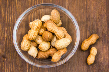 Bowl of peanuts on wooden table top view