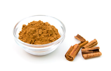 Glass bowl with cinnamon on white background