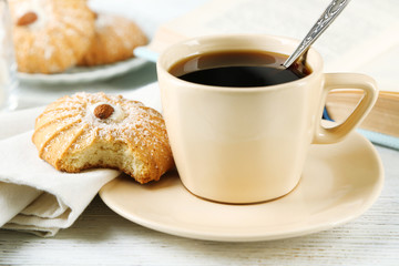 Cup of coffee with tasty cookie on color wooden background