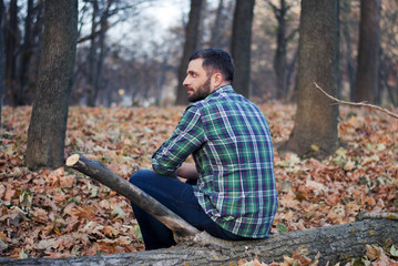 Man sitting on a log in the woods