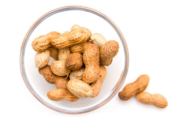 Peanuts on glass bowl on white background top view