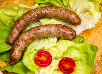 Sausage on wooden cutting board with salad top view