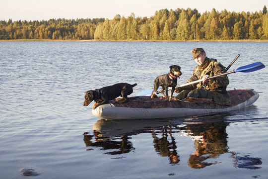 The hunter floats in the boat with two dogs