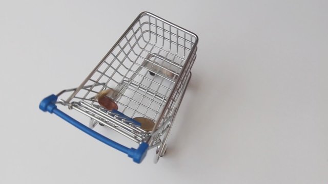 Geldm&uuml;nzen fallen in einen Einkaufswagen