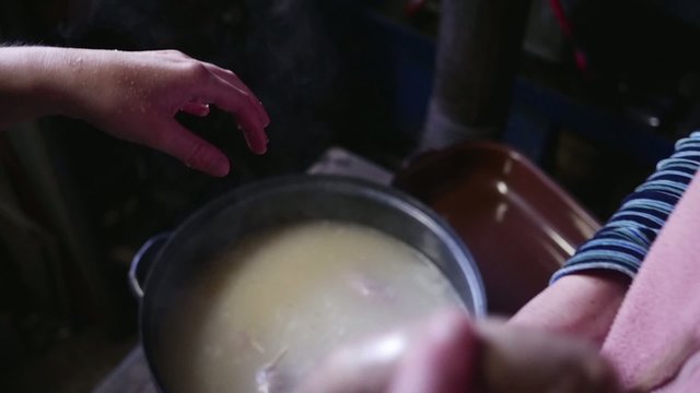 Hand putting homemade sausage into pot in slow motion