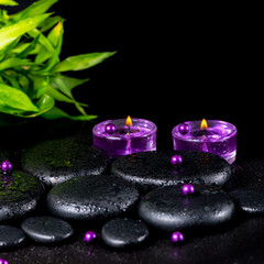 spa concept of zen basalt stones with drops, lilac candles, bead