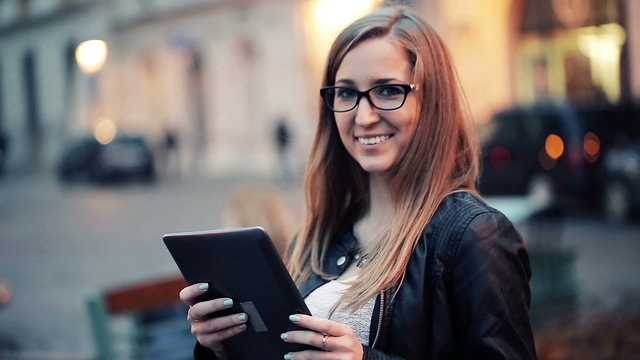 Portrait of young, smiling woman with tablet computer in the cit