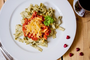 Green herb pasta with bolognese sauce with a glass of wine