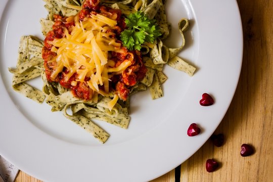 Green herb pasta with bolognese sauce with heart-shape pubbles
