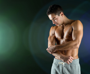 young male bodybuilder injured touching elbow