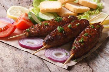 kebabs with vegetables on paper close-up. horizontal