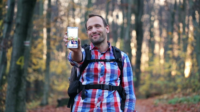 Young, handsome hiker taking selfie with smartphone in forest
