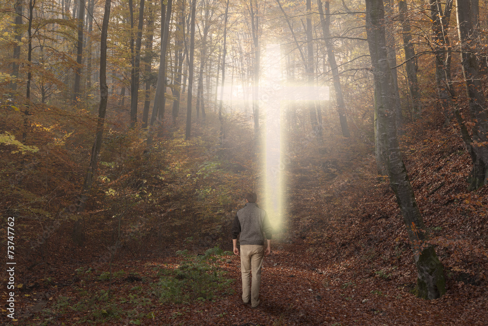 Wall mural Man walking to the corss in an autumn forest