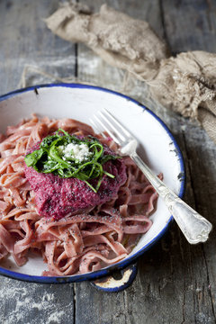 pasta with beetroot pesto, rocket and parmesan on plate
