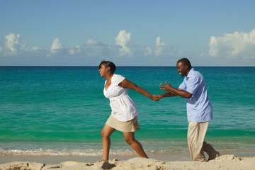 Happy young couple running on the beach.