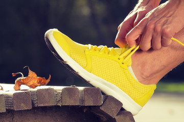 Tying running sneakers on a park bench.