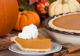 Slice of a pumpkin pie and pumpkins on the background
