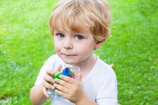 Beautiful toddler boy with glass of berry ice cubes