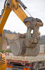 bucket of a bulldozer and a truck in the background