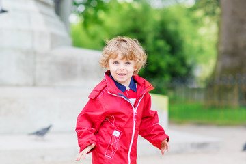 Cute little  boy catching and playing with pigeons in city