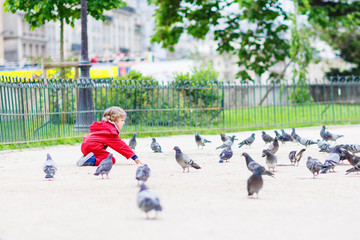 Cute little  boy catching and playing with pigeons in city