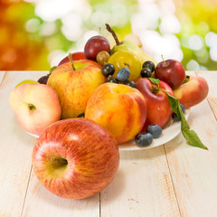 various ripe fruits on a plate on a blurred background