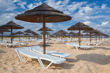 Different parasols and sun loungers on the empty beach on Tavira