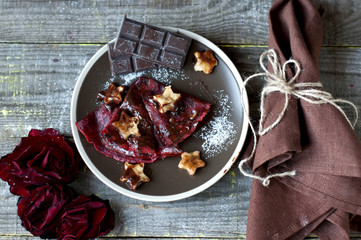 Sweet red pancakes with chocolate - banana topping on wooden tab