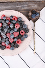 Iced berries on plate, on color wooden background