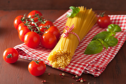raw spaghetti pasta basill tomatoes. italian cuisine in rustic k