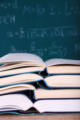 Books on wooden table on blackboard background