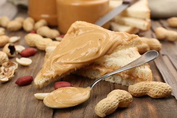 Bread slices with creamy peanut butter on wooden table