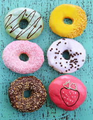 Delicious donuts with glaze on colorful wooden background