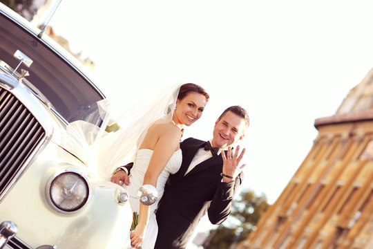 Bride and groom with a white retro car