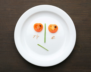 Vegetable face on plate on wooden table