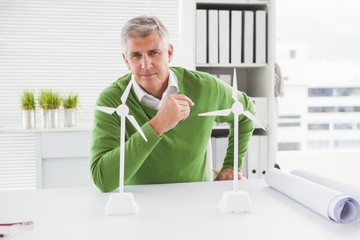 Casual businessman looking at model wind turbines
