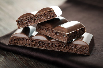 Tasty porous chocolate on wooden table
