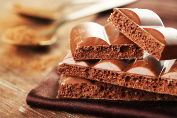 Tasty porous chocolate on wooden table