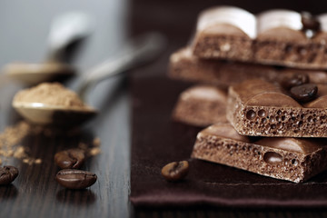 Tasty porous chocolate with coffee beans on table, close up