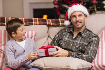 Son giving father a christmas gift on the couch