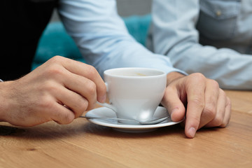 Junger Mann hält Kaffeetasse auf Holztisch